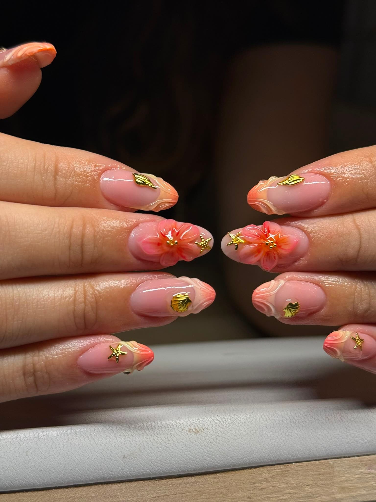 Zomerse nail art in koraal met gouden schelpjes, zeesterren en 3D-bloemen